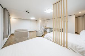 a bedroom with two beds and two chairs and a desk at The Oakra Hotel in Jeju