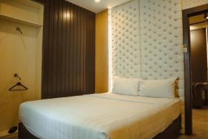 a bedroom with a white bed with a padded headboard at Twin Tower Hotel & Residence in Surabaya