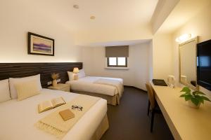 Una habitación de hotel con dos camas y un televisor. en Ful Won Hotel, en Taichung