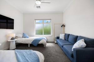 ein Wohnzimmer mit einer blauen Couch und einem Bett in der Unterkunft Aldinga Horizon in Aldinga Beach