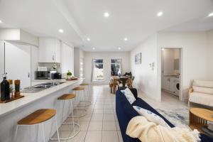 eine Küche und ein Wohnzimmer mit weißen Schränken und blauen Stühlen in der Unterkunft Aldinga Horizon in Aldinga Beach