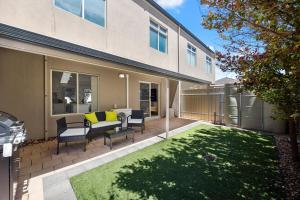 einen Hinterhof mit einem Tisch, Stühlen und einer Liegewiese in der Unterkunft Aldinga Horizon in Aldinga Beach