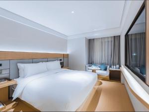 ein Schlafzimmer mit einem großen weißen Bett und einem Fenster in der Unterkunft JI Hotel Shanghai Meiling North Road Subway Station in Shanghai