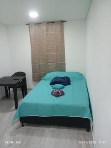 um quarto com uma cama com um cobertor azul e uma mesa em Alojamientos Jamar em Rionegro