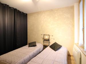 2 Betten in einem Zimmer mit schwarzen Vorhängen in der Unterkunft Beau F3 avec parking et animaux acceptés, proche Thermes - FR-1-415-165 in Le Mont-Dore