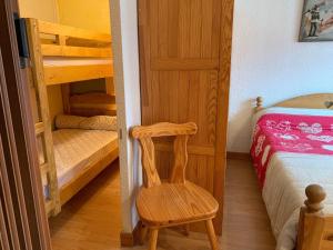 ein Schlafzimmer mit einem Etagenbett und einem Holzstuhl in der Unterkunft Studio-Cabine au Praz de Lys, 4 pers, proche pistes - FR-1-815-30 in Le Praz de Lys