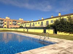 ein Swimmingpool vor einem gelben Gebäude in der Unterkunft Casa adosada con piscina. Paradis St Pere - ES-89-147 in Sant Pere Pescador