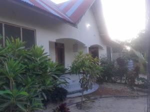 a white house with a red roof and some plants at Faith Under Fire Villa in Migogoni