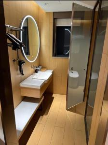 ein Badezimmer mit Waschbecken und Spiegel in der Unterkunft JI Hotel Shanghai Meiling North Road Subway Station in Shanghai