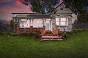 une maison avec une terrasse couverte et des escaliers dans une cour dans l'établissement Clonburn Manor at Sovereign Hill, à Ballarat