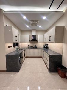 een grote keuken met witte kasten en zwarte aanrechtbladen bij Zeta Mall 2 bedroom Apartment with Swimming Pool in Islamabad +60 foto's