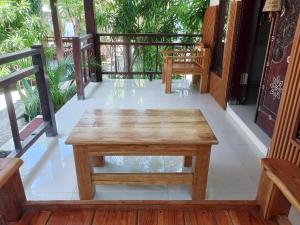eine Holzbank auf einem Balkon mit Bäumen in der Unterkunft Banana Leaf Resort in Gili Trawangan