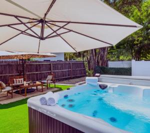 a hot tub in a yard with an umbrella at Central East Austin Luxury Hot Tub & Game Room in Austin