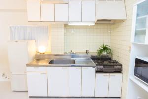 une cuisine avec des armoires blanches et un évier dans l'établissement Miraie Katano Stay, à Kisabe 32 autres photos