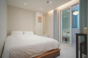 una camera da letto con un letto bianco e una grande finestra di Stay Hello Hongdae Sinchon a Seul