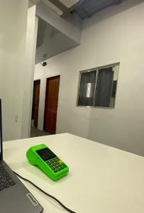 Ein grünes Handy liegt auf einem Tisch neben einem Laptop. in der Unterkunft AeroBelém - Apart & Residence in Belém