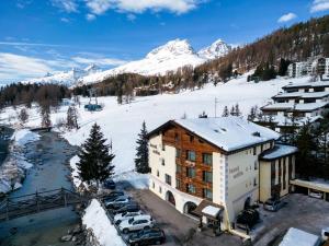 a building with cars parked in front of a snow covered mountain at Hotel Nolda in St. Moritz