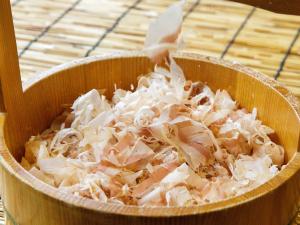 een houten kom gevuld met uien op een tafel bij Nishitetsu Inn Kochi Harimayabashi in Kochi