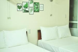 two beds with white sheets and pictures on the wall at Oriio Hotel Cát Bà in Cat Ba +78 photos