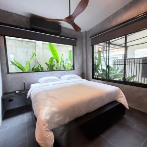a bedroom with a bed and two windows with plants at Sakhu Art Villa in Nai Yang Beach +78 photos