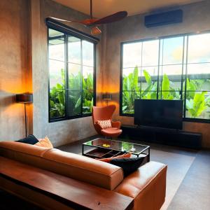 a living room with a couch and a tv at Sakhu Art Villa in Nai Yang Beach