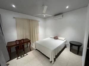 a bedroom with a bed and a table and a chair at Casa playa in Huacas