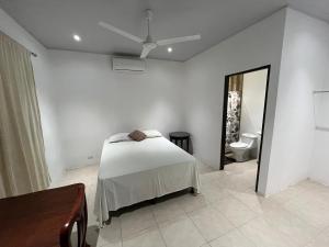 a white bedroom with a bed and a mirror at Casa playa in Huacas