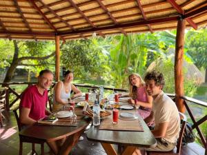 a group of people sitting around a wooden table at Sunrise Udawalawe Resort in Udawalawe +16 photos