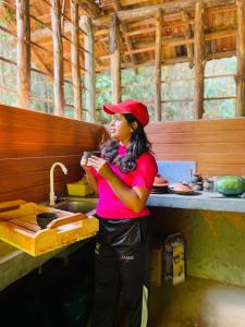 a woman standing in front of a kitchen sink at Belihuloya Fattah Camping Resort in Belihul Oya