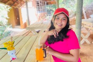 a woman in a red shirt holding a drink at Belihuloya Fattah Camping Resort in Belihul Oya