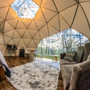 un soggiorno con un divano e una grande parete di vetro di Glamping, Sauna, Jacuzzi en Mazamitla a Mazamitla