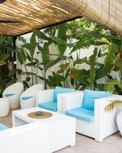 a patio with white chairs and a table and plants at The White Bay Lombok in Kuta Lombok