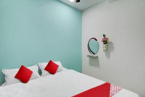 a bedroom with a bed with red pillows and a mirror at Hotel O Kings in Pānchgaon +26 photos