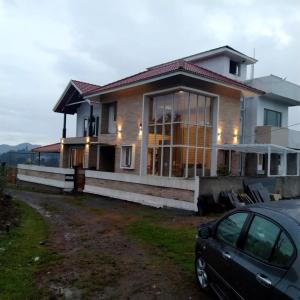 a house with a car parked in front of it at Nidha Home in Ooty