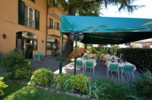 un patio con mesas y sillas bajo una sombrilla azul en Albergo Ponte Vecchio, en Cernobbio