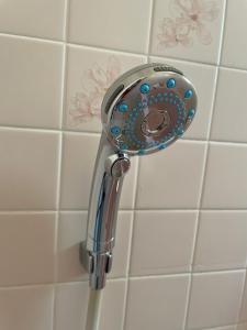 a shower head in a bathroom with white tiles at kumanonisumu! in Kumano