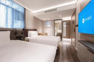 a hotel room with two beds and a flat screen tv at Hanting Hotel Shanghai Huangxing Road Subway Station in Shanghai