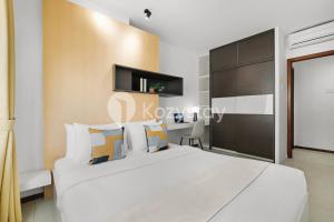 a bedroom with a large white bed and a desk at Javen by Kozystay - Thamrin in Jakarta