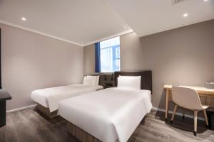 a hotel room with two beds and a desk at Hanting Hotel Shanghai Huangxing Road Subway Station in Shanghai
