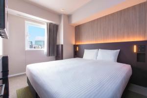 a hotel room with a large bed and a window at Villa Fontaine Tokyo Kudanshita in Tokyo