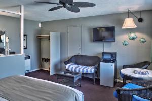 a bedroom with a bed and a tv and a chair at Lovers Point Inn in Pacific Grove