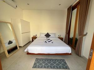 a bedroom with a white bed and a large mirror at Casa Gemellia Brand New 2BR in Umalas in Kerobokan