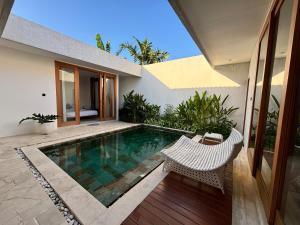 a swimming pool with two chairs and a house at Casa Gemellia Brand New 2BR in Umalas in Kerobokan