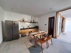 a kitchen with a table and a stainless steel refrigerator at Casa Gemellia Brand New 2BR in Umalas in Kerobokan