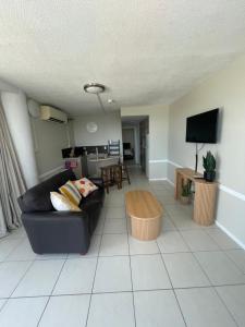 a living room with a black couch and a tv at Heart of Yeppoon - Ocean View Apartment in Yeppoon