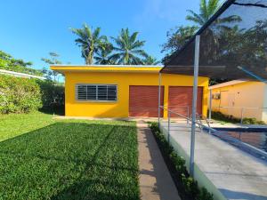 a yellow house with a lawn in front of it at Pura Vida - Villa Lisa in Parrita