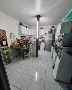 eine Küche mit weißen Geräten und einem Tisch darin in der Unterkunft Quarto com ar Perto Furg,Praia! in Rio Grande