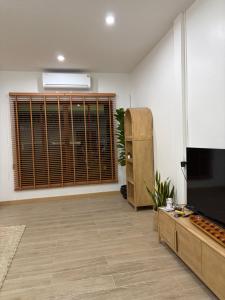 ハジャイにあるAma'homeの大きな窓とテレビのあるリビングルーム