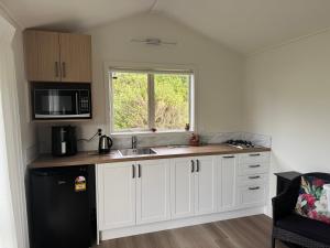 a kitchen with white cabinets and a black refrigerator at Newlands Bed and Breakfast in West Melton