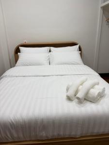 Una cama blanca con dos toallas encima. en Ama'home, en Hat Yai